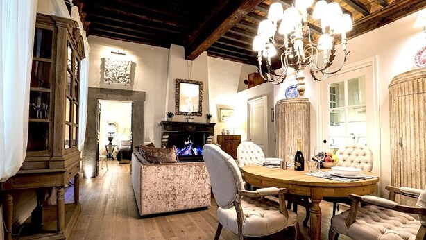 A cozy dining area with a wooden table, upholstered chairs, and a chandelier.