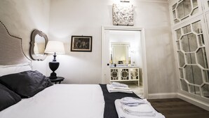 A neatly arranged hotel room with a bed, bedside table, lamp, and a large mirror.