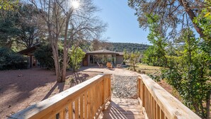 A wooden deck leading to a building with a covered patio area, surrounded by trees and a clear sky. - Brand New 2 Bed/2.5 Bath Renovation, Centrally Located in Sedona (Sedona)