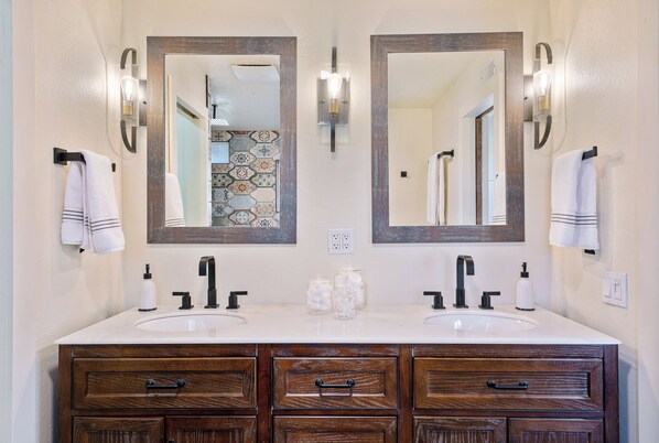 A bathroom with two sinks, wooden cabinets, and wall-mounted mirrors.