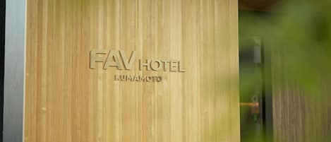 Un muro di legno con la scritta "FAV HOTEL KUMAMOTO" incisa.
