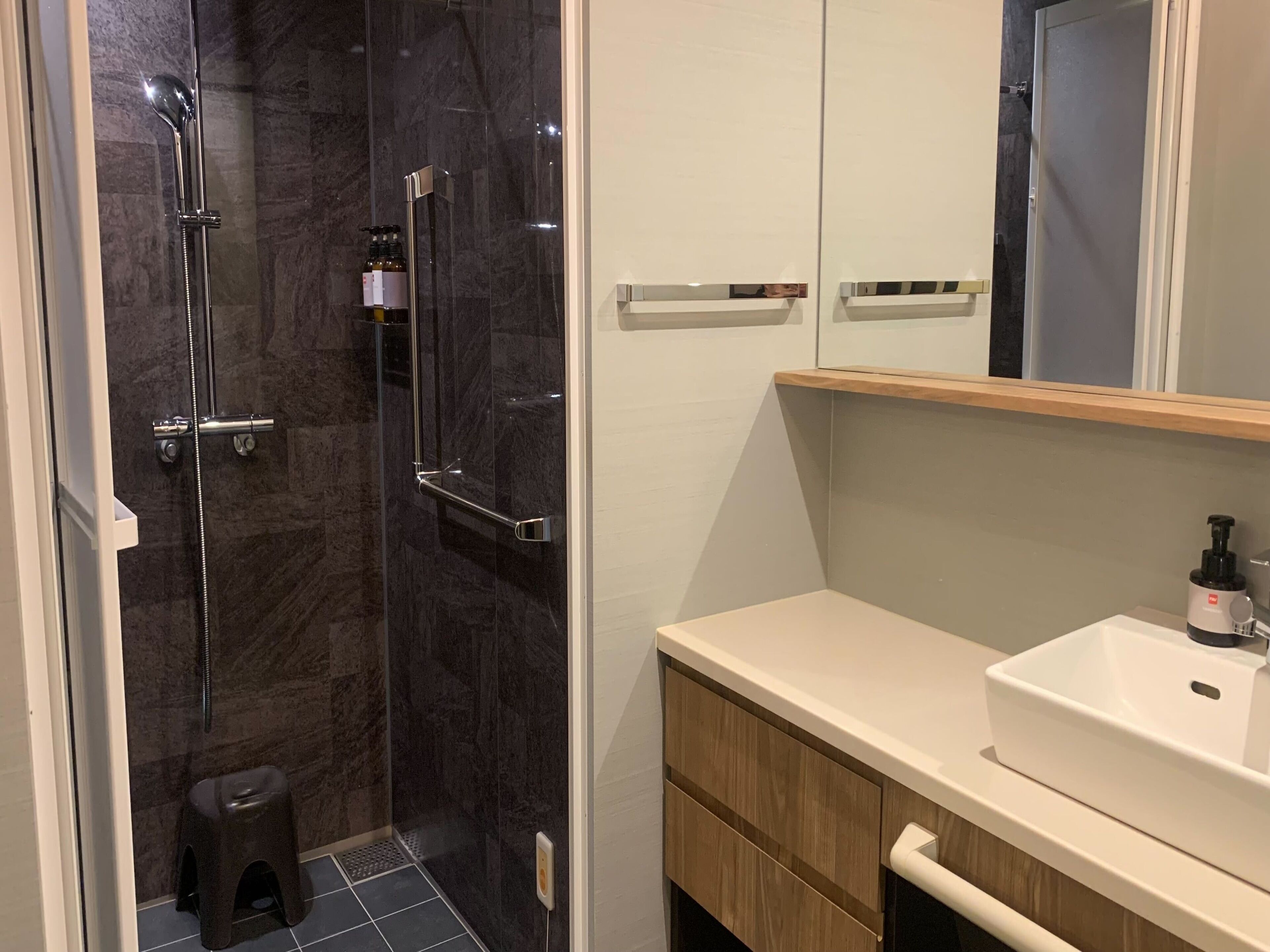A modern bathroom with a glass-enclosed shower, a white sink, and wooden cabinetry.
