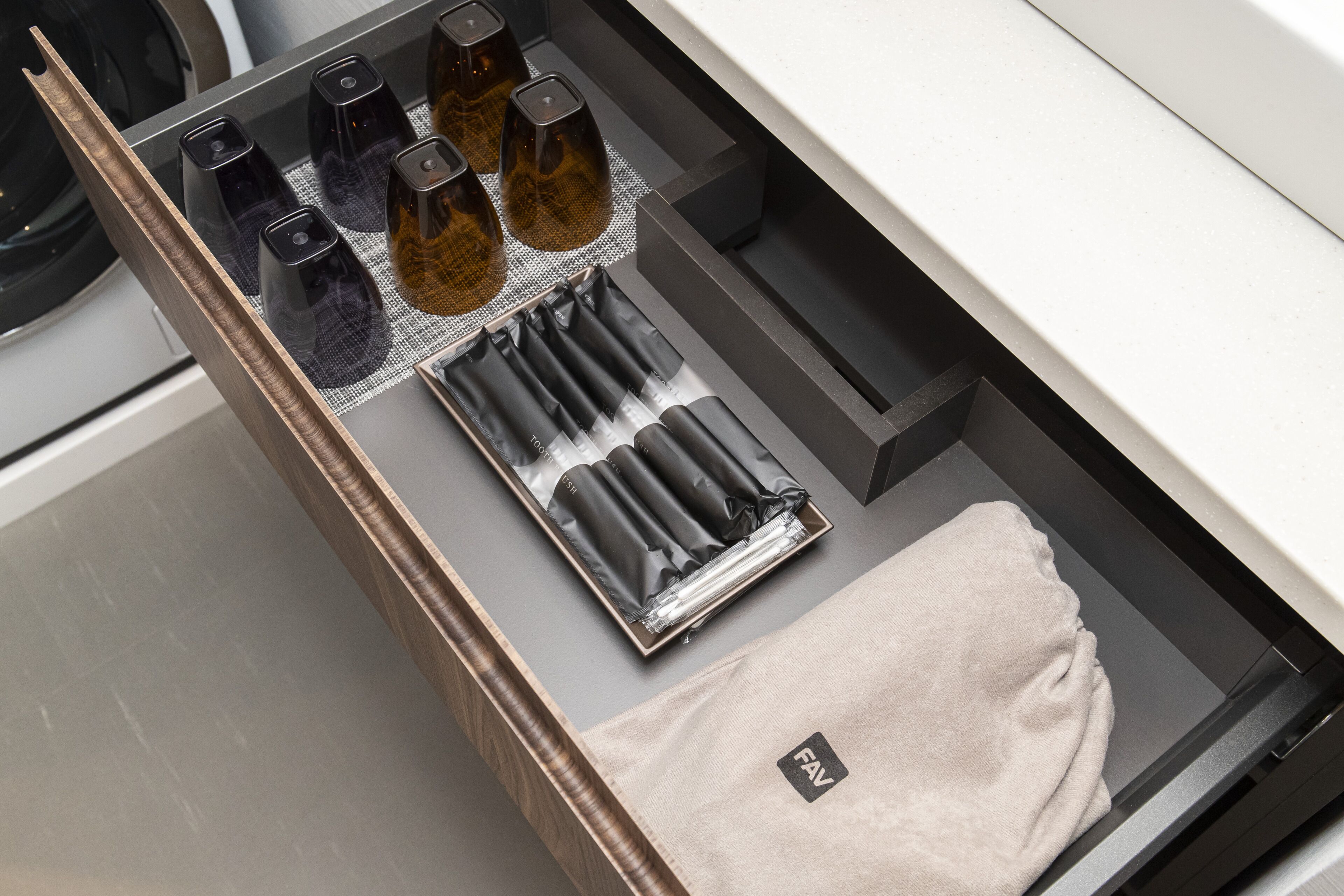 Un cajón con objetos ordenados, como botellas, una caja de pañuelos y un paño color beige.