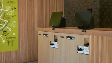 A reception desk with a wooden finish and a green wall with doodles. There are two monitors on the desk, and a map is visible on the wall.