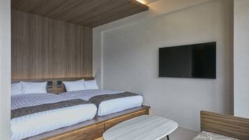 A modern bedroom with two beds, a flat-screen TV, and a small table.