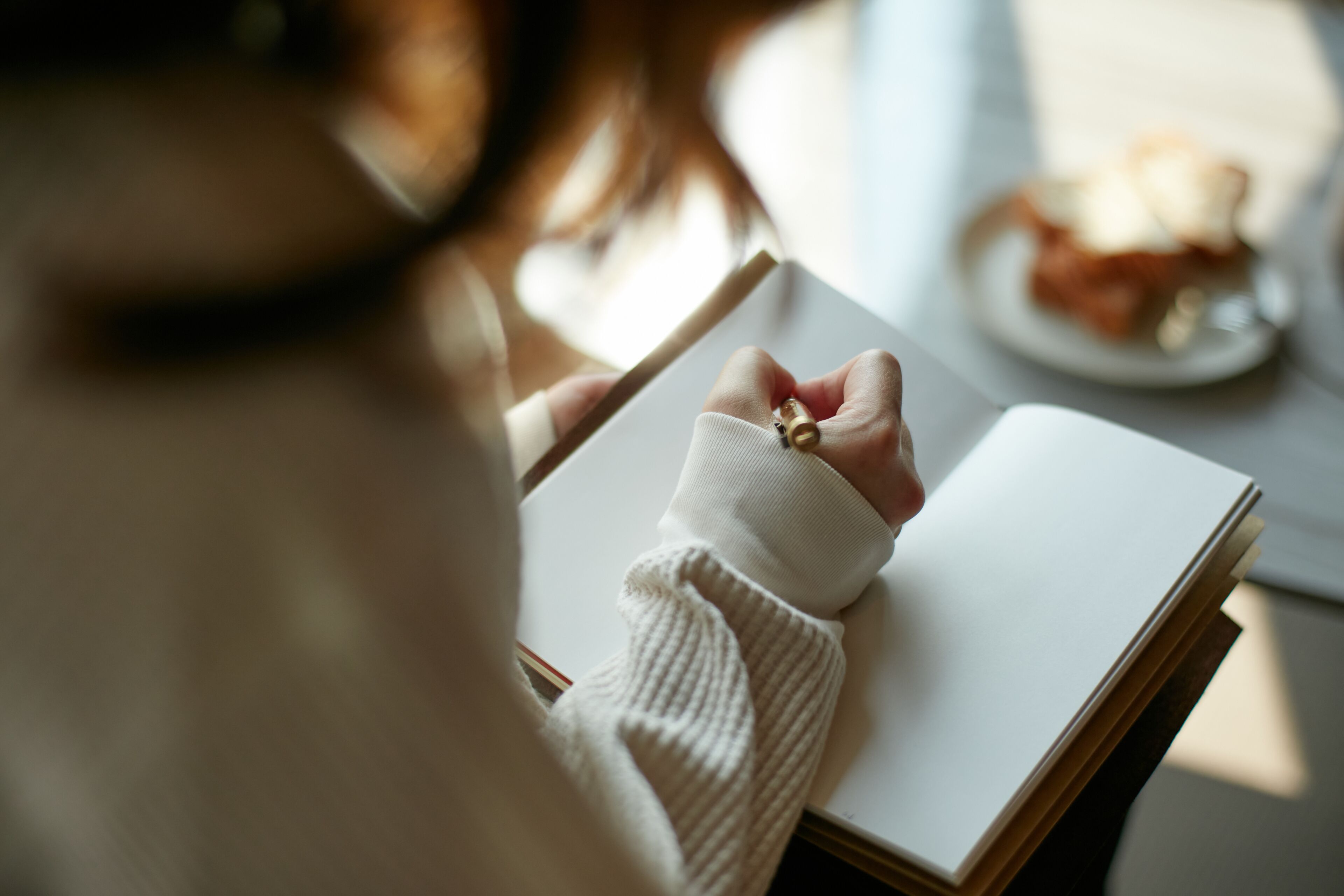 Una persona sentada a una mesa con un libro y un plato de comida.