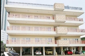 Un immeuble à plusieurs étages doté de balcons, d’un espace de stationnement et d’une entrée couverte.