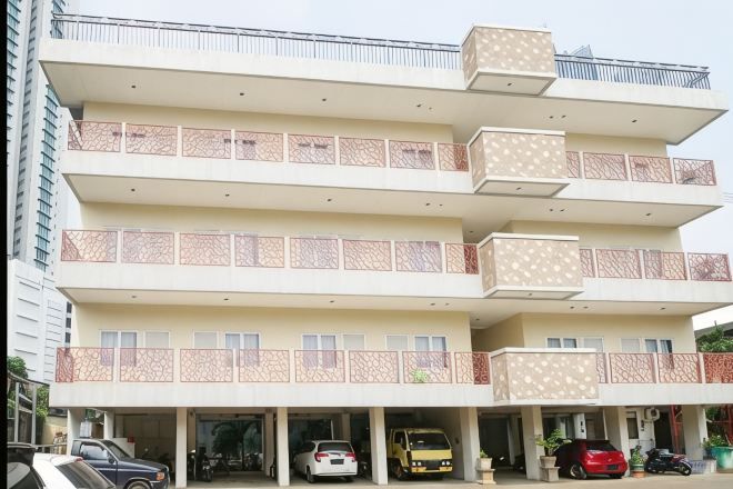 A multi-story building with balconies and a parking area.