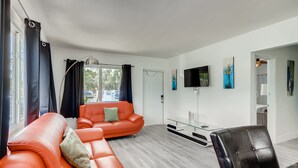 Uma sala de estar moderna com um sofá, uma poltrona e uma televisão na parede.