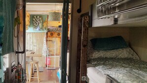 A compact room with bunk beds, a kitchenette, and a small dining area.