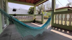 Un hamac sur une terrasse carrelée, agrémentée d’une clôture blanche décorative, d’un mur végétal et de plantes suspendues.