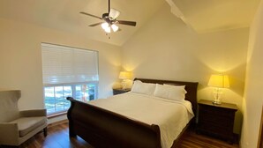 A bedroom with a large bed, a chair, a nightstand with a lamp, and a ceiling fan. - Cabin B (Casa Blanca), 1BR/1BA, Sleeps 4, Porch, Grill (Kerr County)