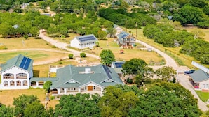 Un quartier résidentiel comprenant plusieurs maisons, dont une grande maison dotée de panneaux solaires et une plus petite avec un garage.