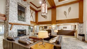 A spacious lobby with a stone fireplace, leather seating, and a reception desk.