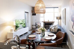 A modern living room with a dining area, a fireplace, and a television.