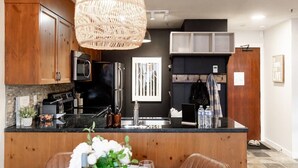 Una cocina moderna con una isla central, electrodomésticos de acero inoxidable y una lámpara colgante.