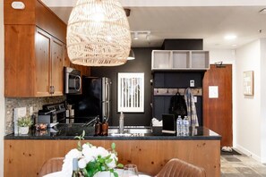 A modern kitchen with a central island, stainless steel appliances, and a hanging light fixture.