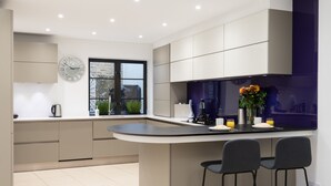 A modern kitchen with a central island, bar stools, a clock, and a window with a view. - SUPERB 3 BEDROOM AND OFFICE COVENT GARDEN HOUSE (London)