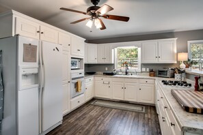 A kitchen with white cabinets, a built-in oven, a microwave, a gas stove, and a ceiling fan. - Gooseberry House - Full 3 bedroom, 2.5 bath house rental across the road from Campground. Inculdes access to communal areas of campground including Nantahala River and self-guided farm tour. (Franklin)