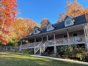 A two-story house with a covered porch and a staircase leading to the second floor. - Gooseberry House - Full 3 bedroom, 2.5 bath house rental across the road from Campground. Inculdes access to communal areas of campground including Nantahala River and self-guided farm tour. (Franklin)
