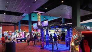 Una sala de juegos con diversas máquinas y una pantalla grande.