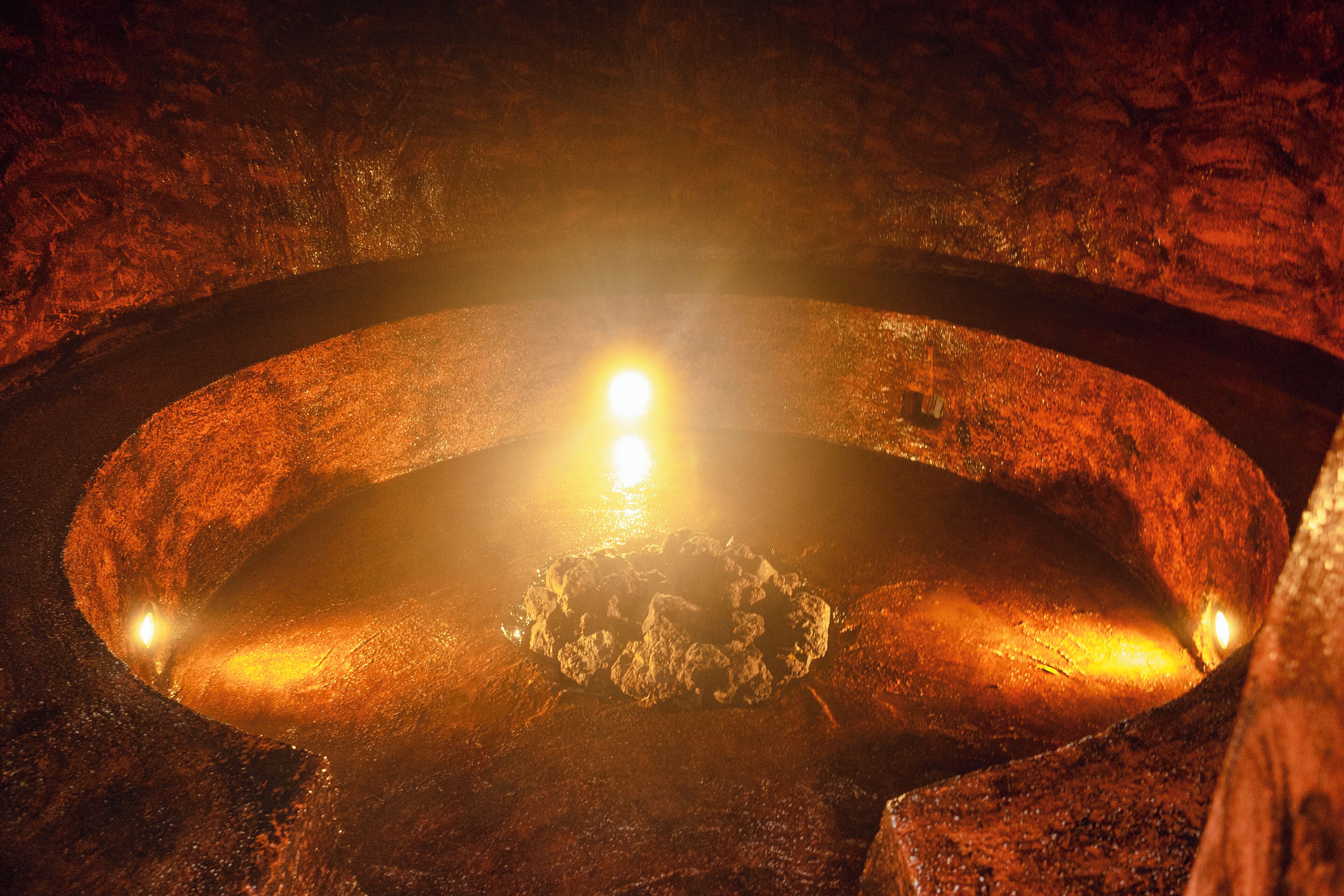 A circular metallic structure with a central glowing light source, surrounded by a rough, textured surface.