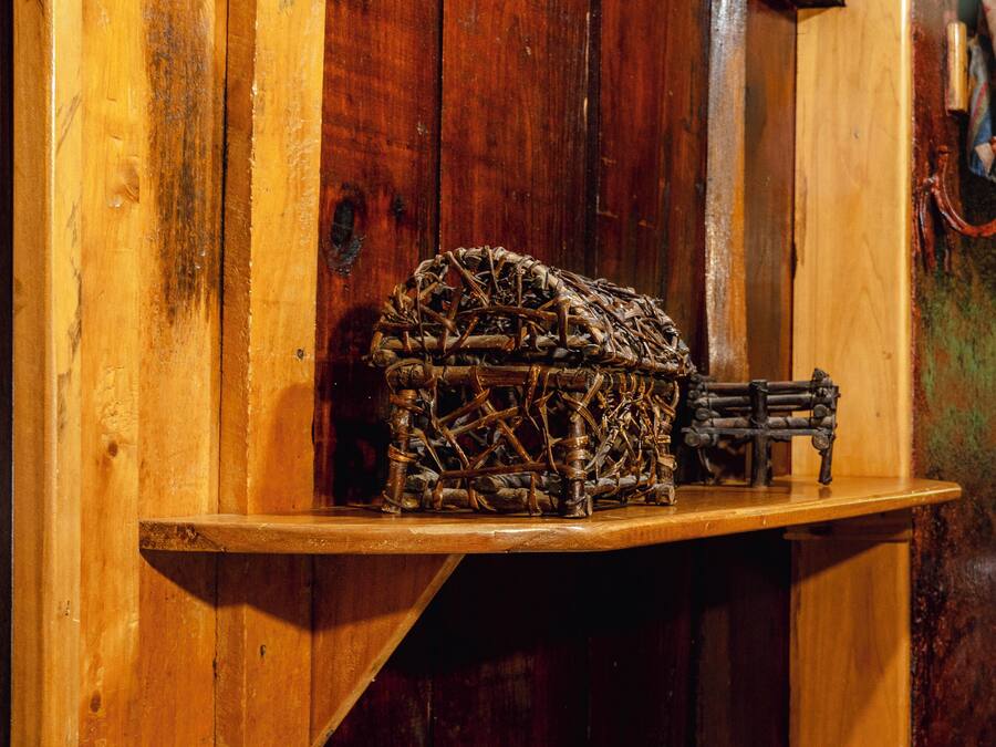 A wooden shelf with a woven basket and rolled towels.