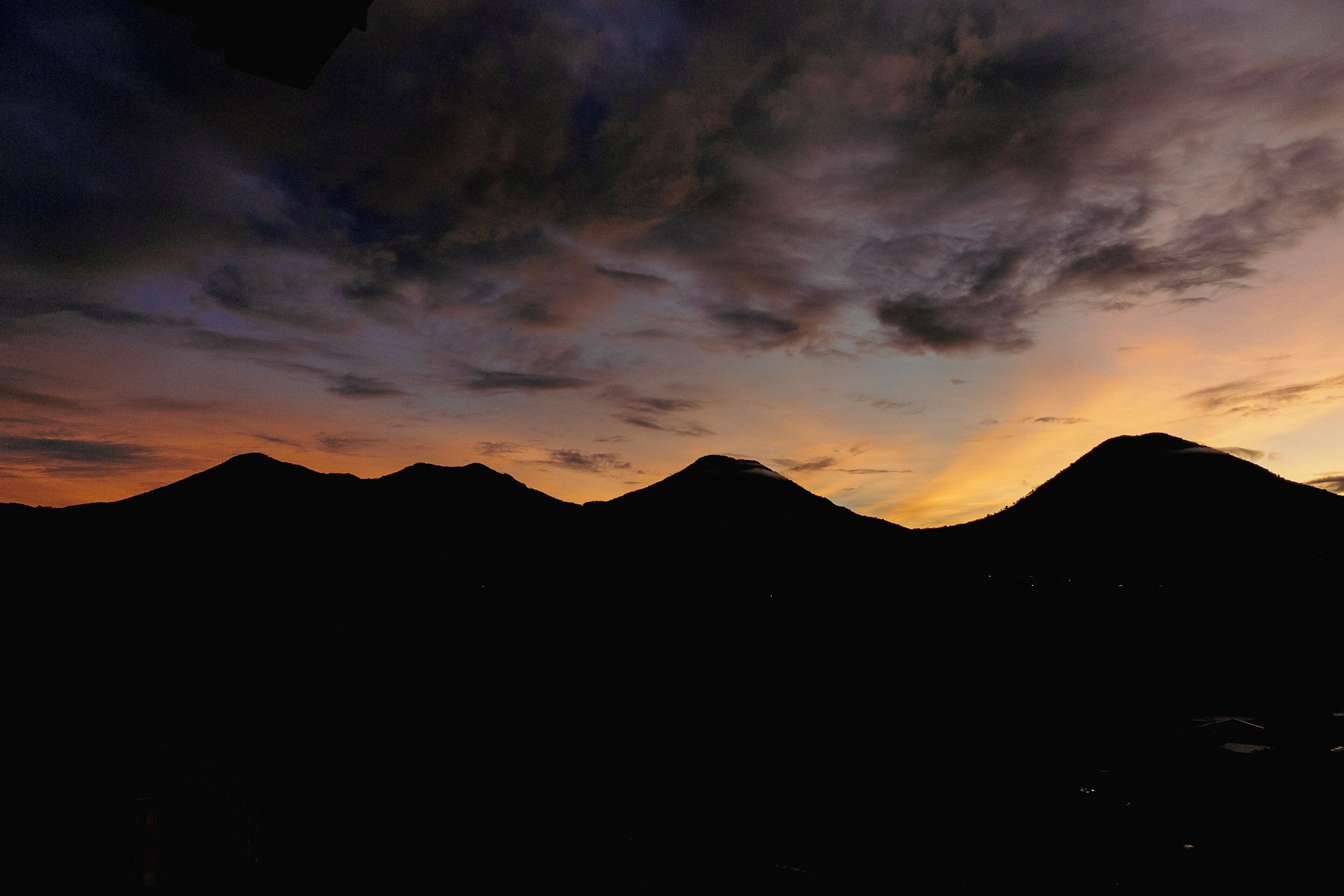 A mountain range silhouette against a sunset sky.
