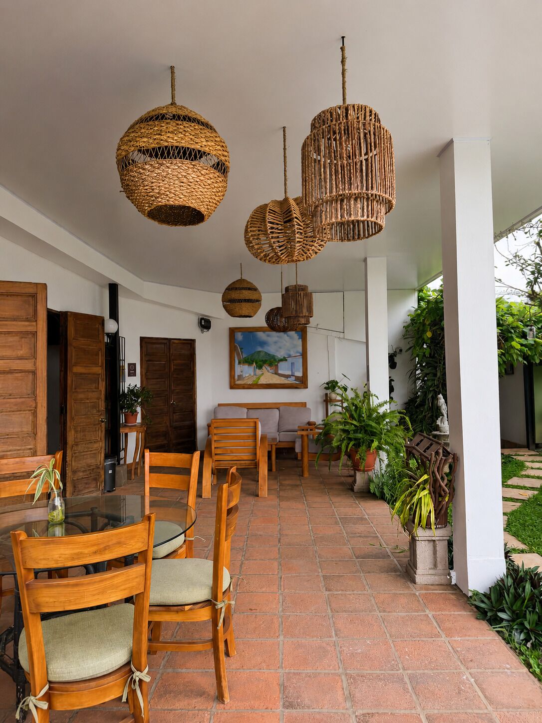 A spacious indoor area with a tiled floor, wooden furniture, and hanging wicker chandeliers.
