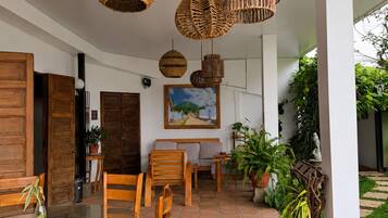 A spacious indoor area with a tiled floor, wooden furniture, and hanging wicker chandeliers.