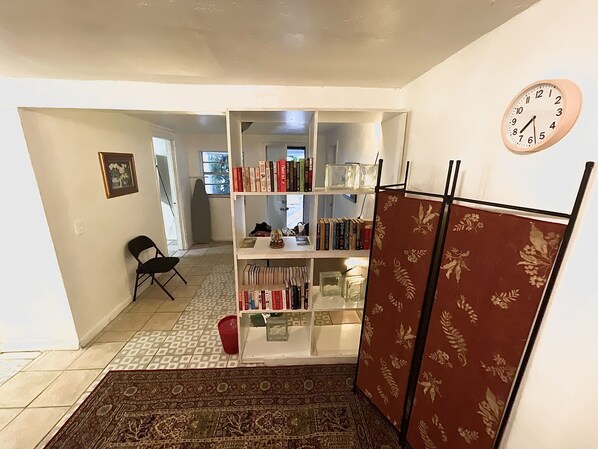 Une pièce avec une bibliothèque, une horloge et un tapis à motifs.