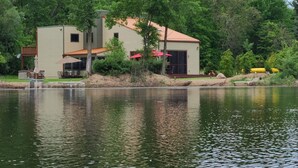 Una casa frente al lago con un patio, mobiliario exterior y un muelle.