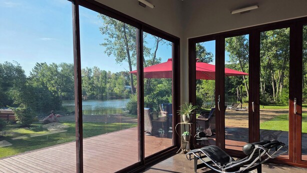 Una habitación con ventanas amplias, una terraza y una silla de descanso.