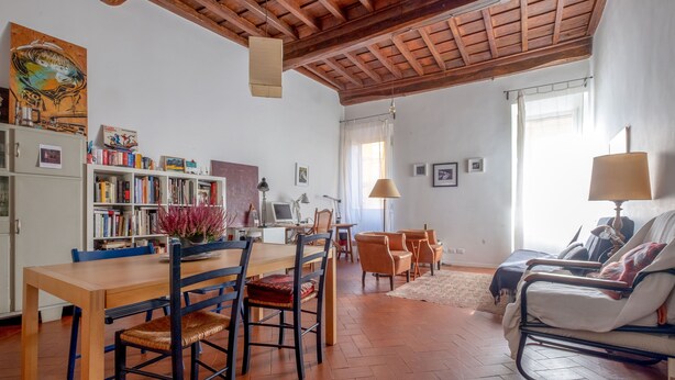 Un salón espacioso con una mesa de comedor de madera, sillas, un sofá y una estantería llena de libros.