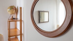 Un espejo redondo con marco de madera sobre una pared blanca.