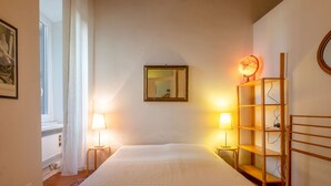 Una habitación de hotel con una cama grande, dos lámparas de noche, una estantería de madera y un globo terráqueo en un estante.