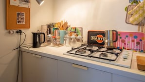 Una cocina con estufa a gas, cafetera y diferentes utensilios de cocina.