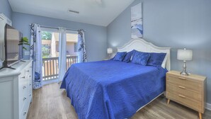 Un dormitorio con cama, cómoda, mesita de noche y ventilador de techo.