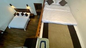 Quarto com duas camas, uma cabeceira de madeira e uma mesinha.