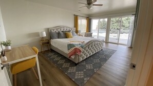 A bedroom with a bed, a desk, a chair, a ceiling fan, and a view of the outdoors. - Lakefront Oasis - Lakefront w/ Views, Private Shared Dock, Wrap Around Deck (Polson)