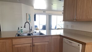A modern kitchen with wooden cabinets, a stainless steel sink, and a dishwasher. - Lakefront Oasis - Lakefront w/ Views, Private Shared Dock, Wrap Around Deck (Polson)
