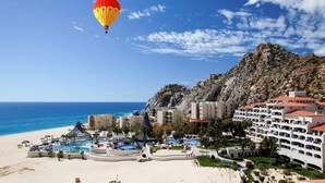 A coastal resort with multiple swimming pools, a beach, and a hot air balloon in the sky. - Luxurious Penthouse Suite on the Ridge or Beachfront side- Playa Grande Resort  (Cabo San Lucas)