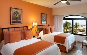 A hotel room with two beds, a large window with a view of the ocean, and a ceiling fan. - Luxurious Penthouse Suite on the Ridge or Beachfront side- Playa Grande Resort (Cabo San Lucas)
