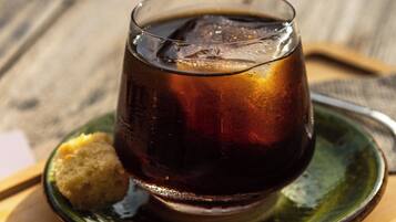A glass of iced tea on a wooden table with a green plate and a biscuit.