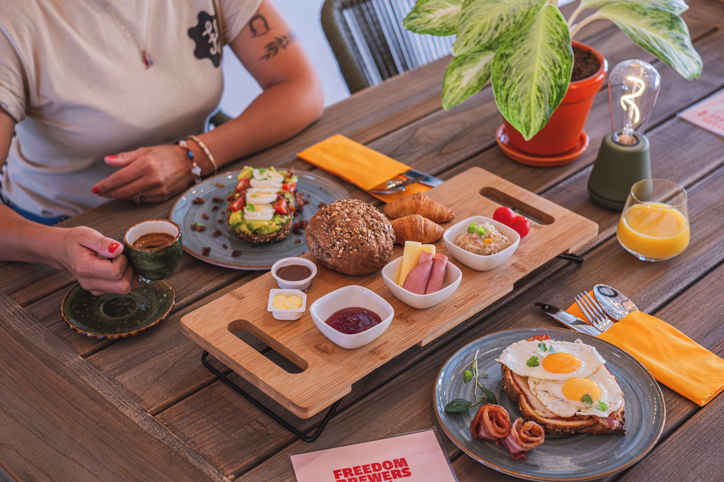 A wooden table with breakfast items including croissants, eggs, and a plate of food.