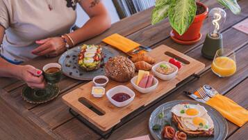 A wooden table with breakfast items including croissants, eggs, and a plate of food.