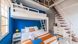 Un dormitorio moderno con una cama nido, una escalera y un aparador blanco.