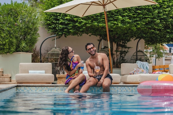 Una piscina al aire libre, sombrillas, sillones reclinables de piscina