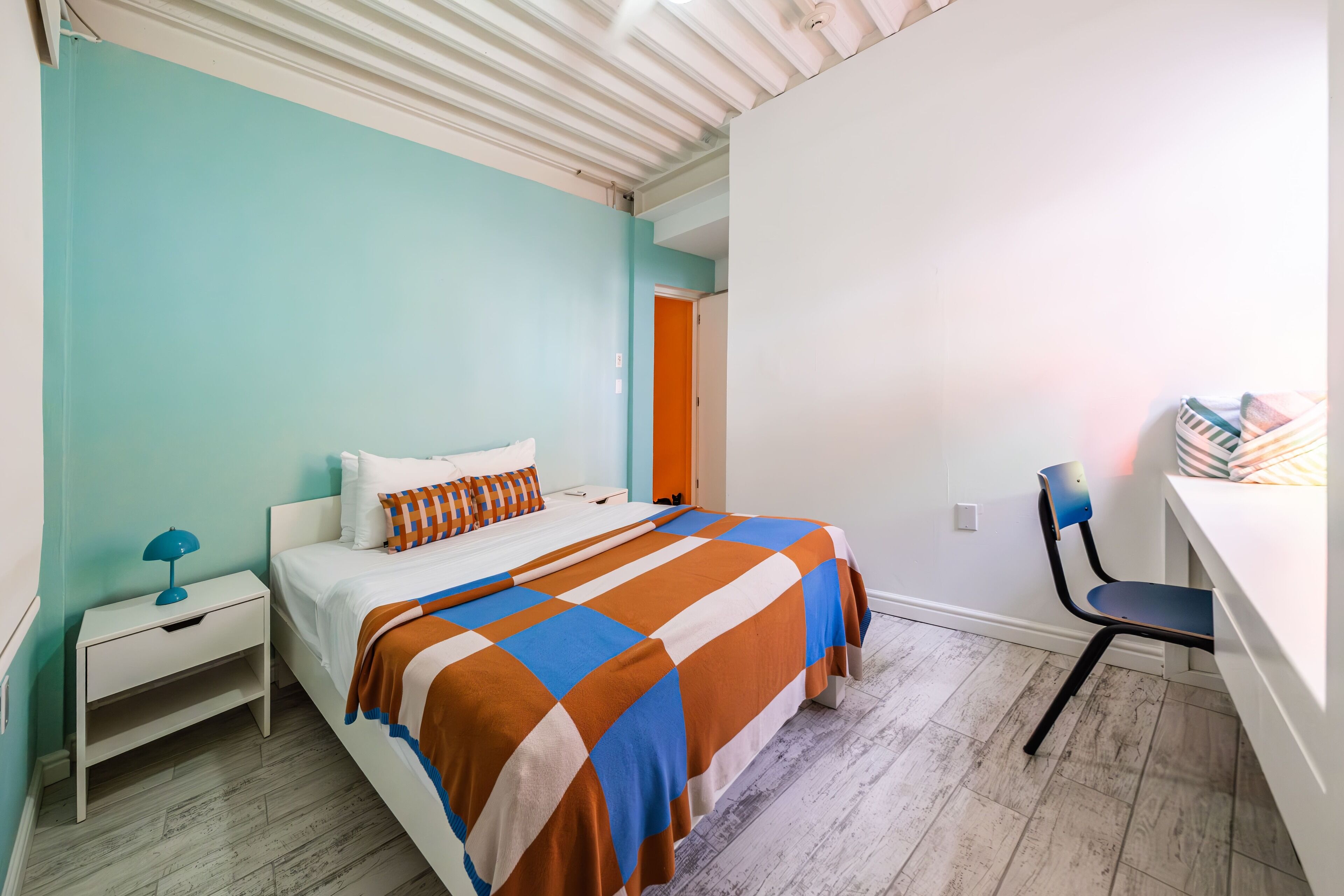 Ein Schlafzimmer mit Bett, Nachttisch, Schreibtisch und Stuhl.