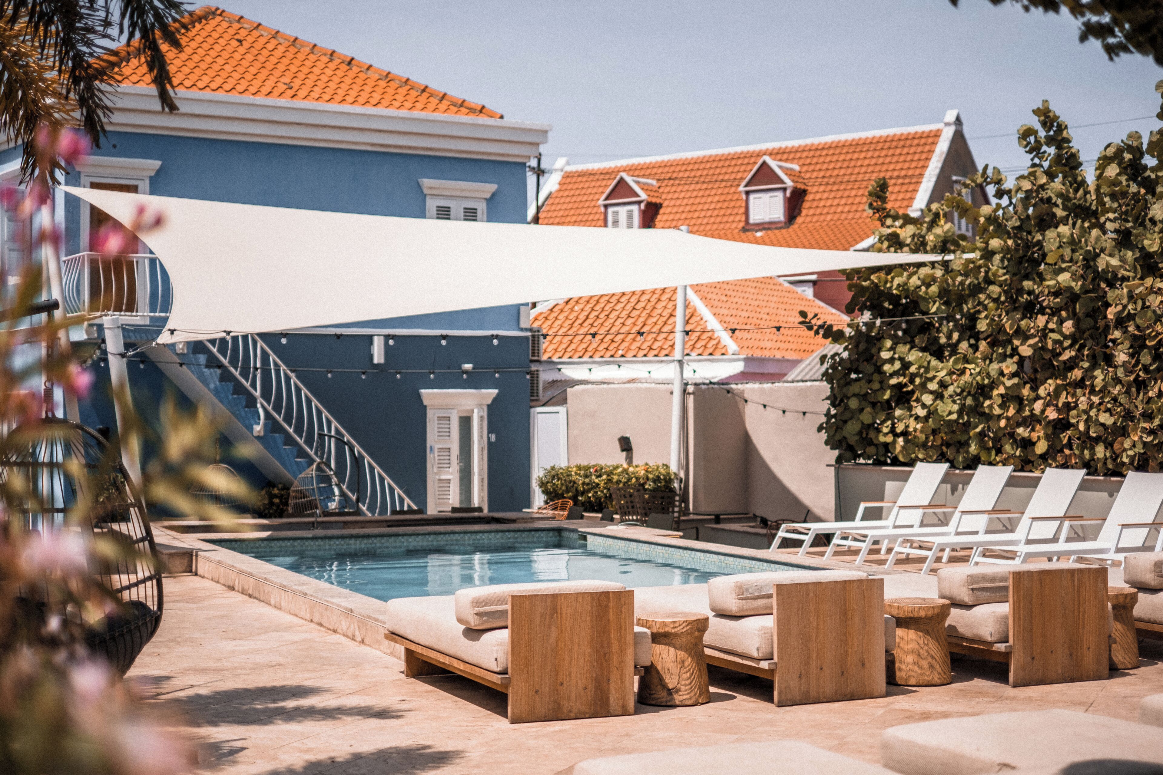 A pool area with lounge chairs and a covered seating area.